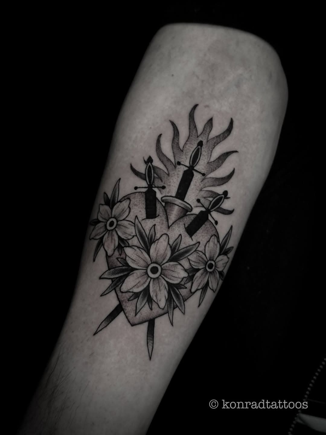 Black and grey tattoo of a dagger with flowers and flames on forearm in illustrative blackwork style