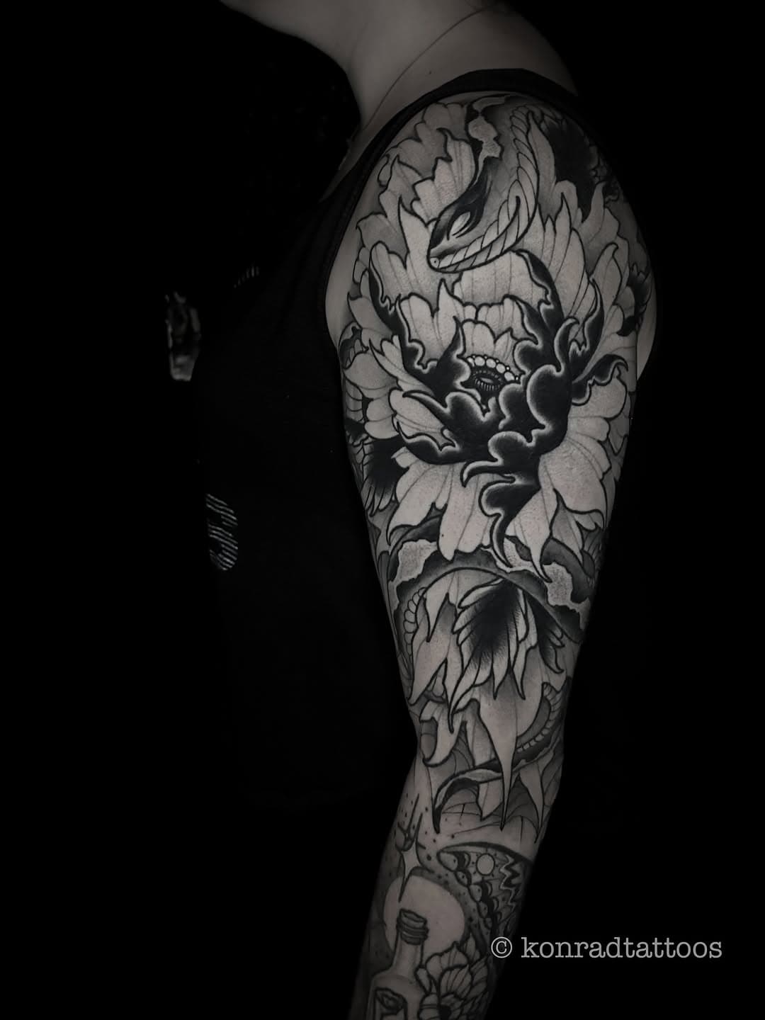 Black and grey full sleeve tattoo featuring a snake emerging from peonies with clouds in traditional Japanese style