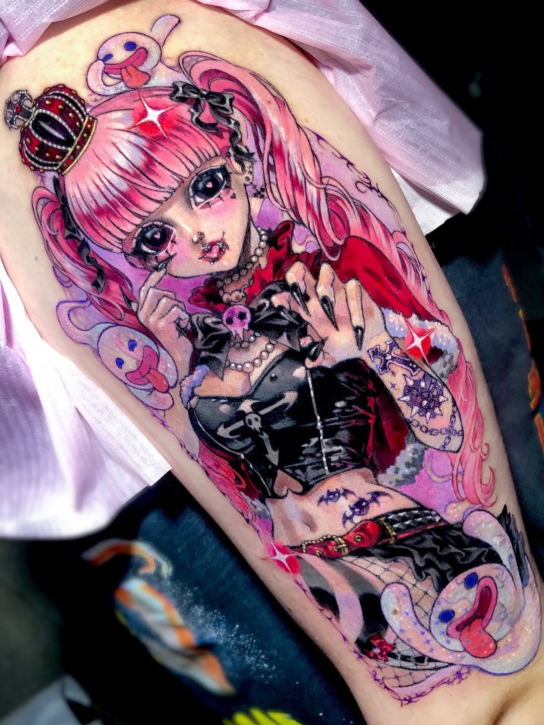Colorful anime-style thigh tattoo of a pink-haired character in gothic lolita outfit with crown, surrounded by kawaii elements