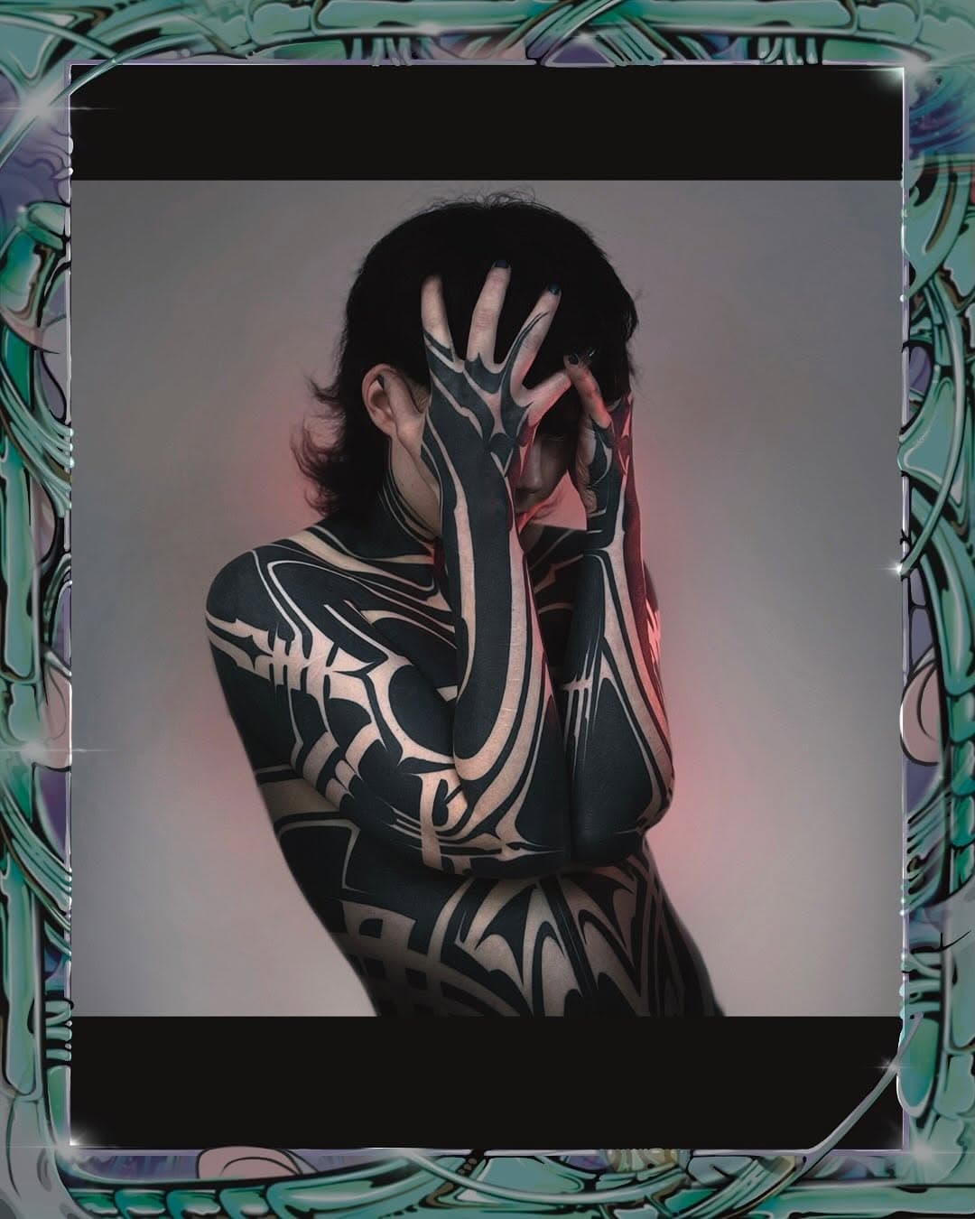 Person with extensive black tribal-style ornamental tattoos covering their back, arms, and hands in bold geometric patterns