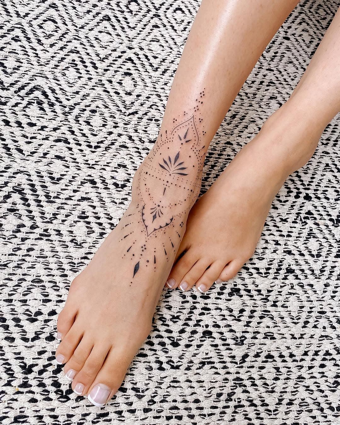 Delicate dotwork ankle and shin tattoo featuring geometric shapes, celestial moon phases, botanical leaves, and decorative line patterns