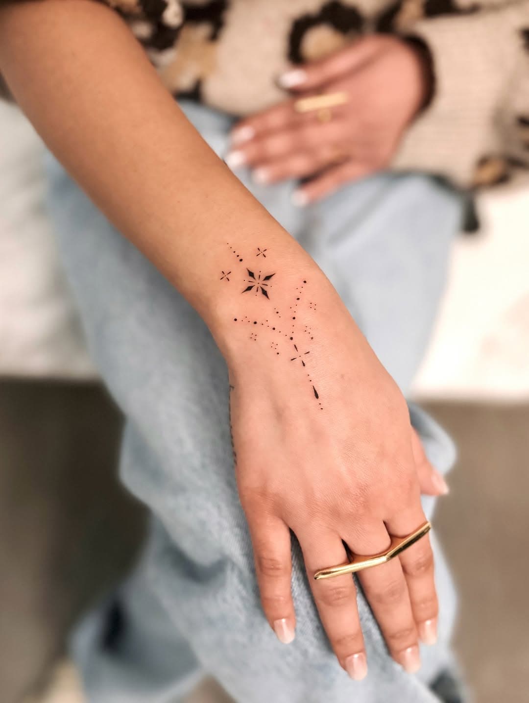 Delicate dotwork star and geometric line tattoo on inner forearm with celestial constellation design