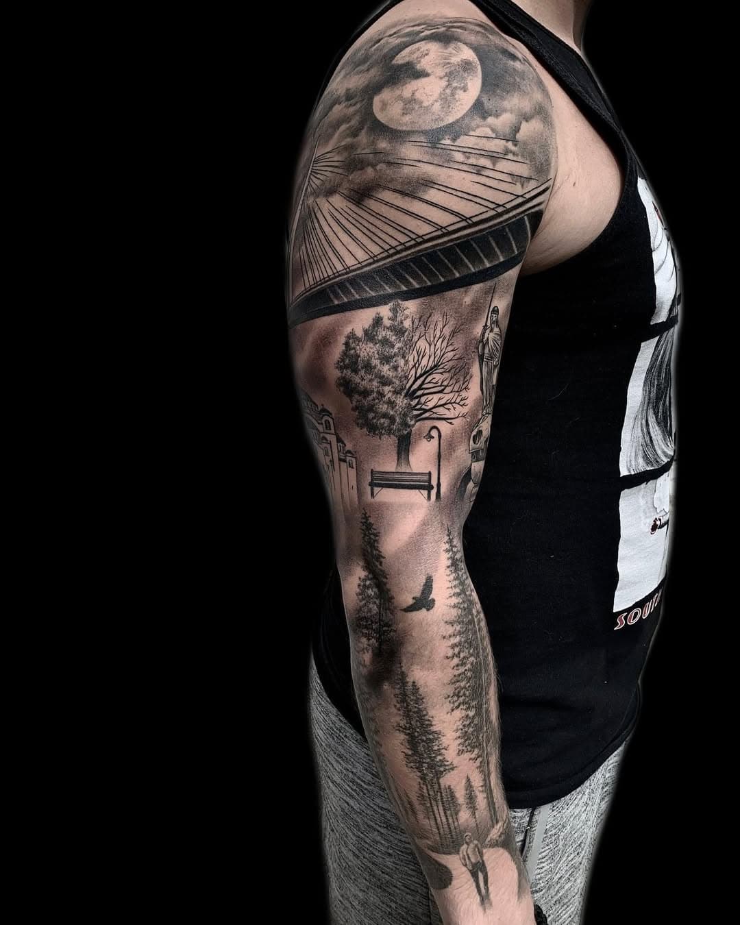 Full sleeve tattoo featuring realistic landscape with moon, geometric lines, park bench, trees, lamp post, and forest path in black and grey