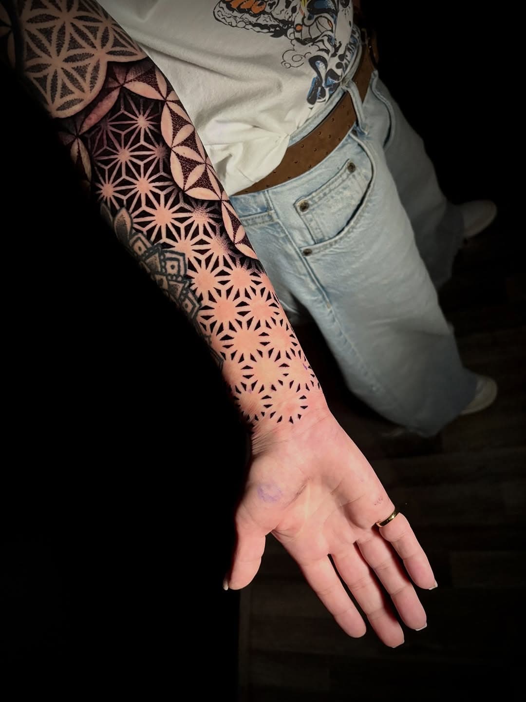 Intricate geometric blackwork sleeve tattoo featuring repeating star patterns and sacred geometry designs flowing down the forearm