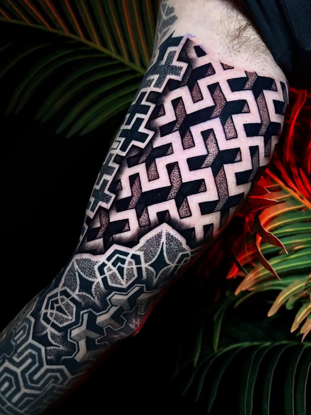 Geometric blackwork tattoo sleeve featuring intricate interlocking angular patterns and dotwork hexagonal mandala designs on forearm
