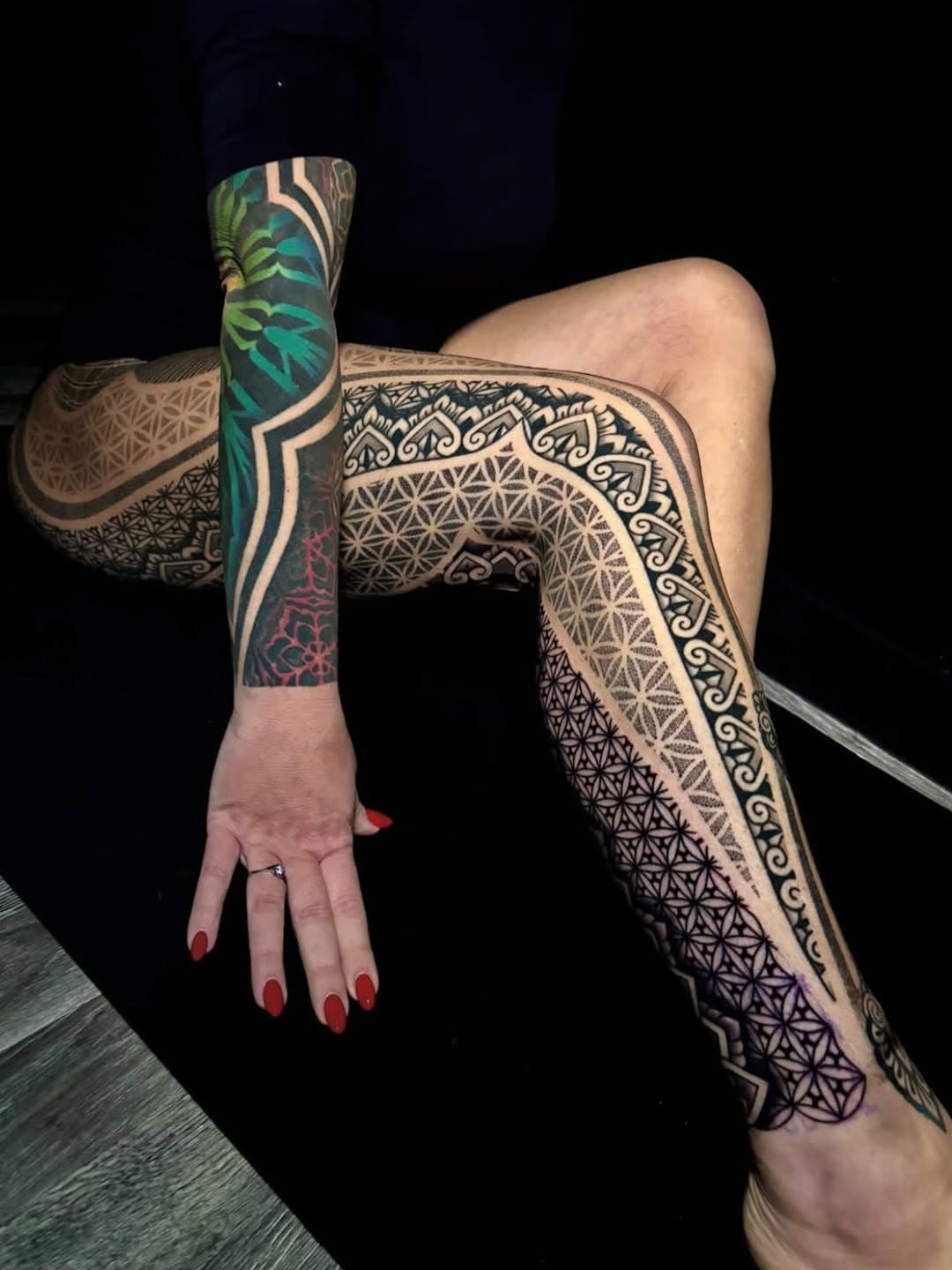 Geometric blackwork leg sleeve featuring intricate sacred geometry patterns, tribal designs, and tropical botanical elements in black ink with colored