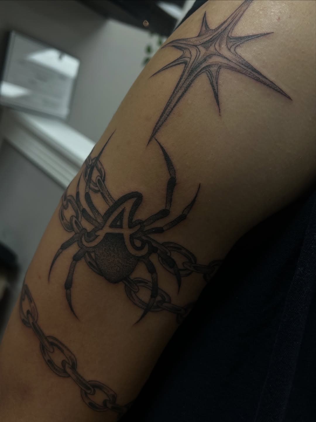 Black and grey tribal-style tattoo featuring sharp geometric points and curved organic elements wrapping around shoulder and upper arm