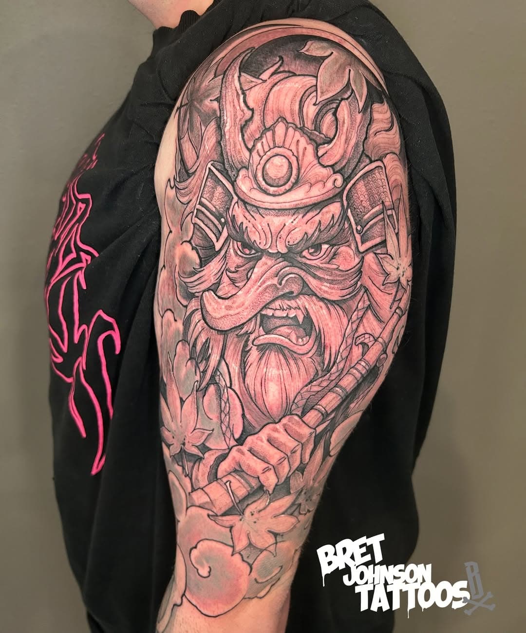 Japanese-style samurai warrior tattoo sleeve with ornamental helmet, fierce expression, and cherry blossoms in black and grey realism