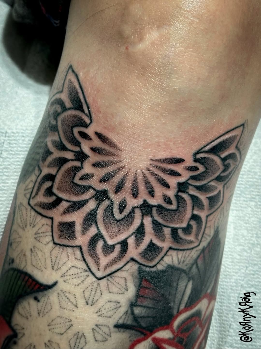 Neo-traditional black and grey ornamental moth tattoo with decorative wings on inner arm, surrounded by floral elements