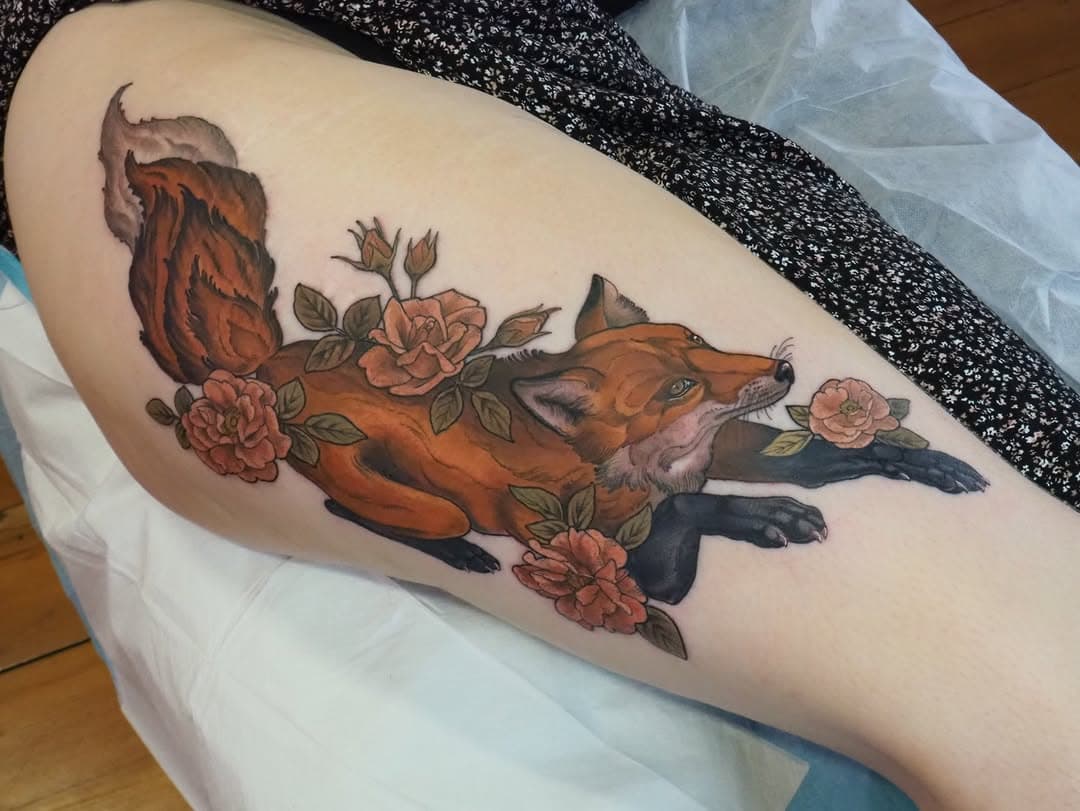 A neo-traditional thigh tattoo depicting a fox surrounded by pink roses and green foliage in warm earth tones